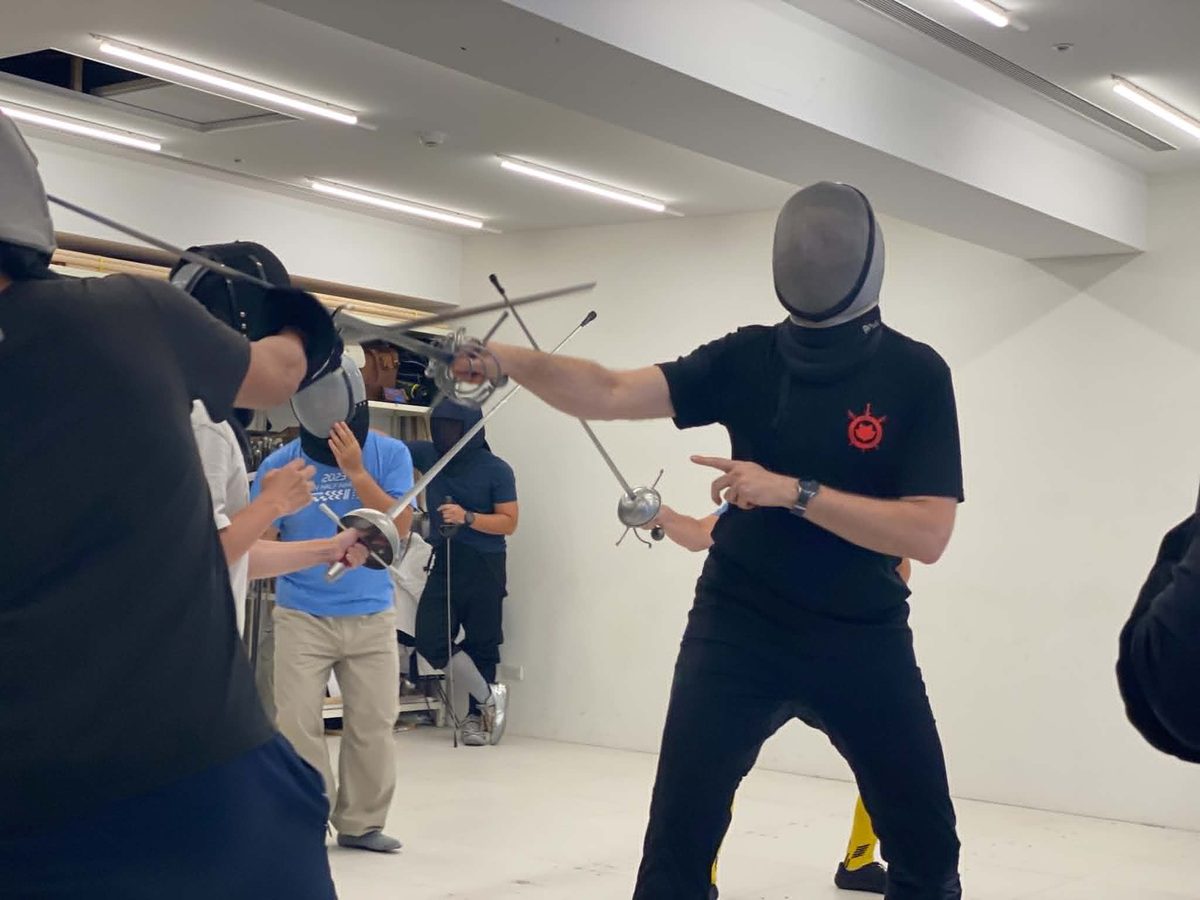 Devon Boorman, wearing a fencing mask, demonstrating a rapier bind with a participant during the Taipei instructor intensive